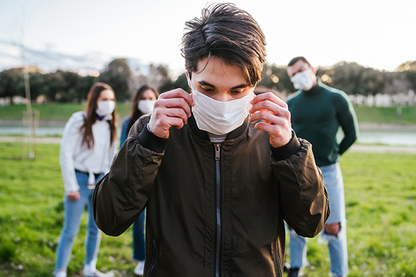 Group of teenagers friends at park wearing medical masks to protect from infections and diseases - Conceptual Coronavirus virus quarantine - Copy space - Multiracial people having fun together
